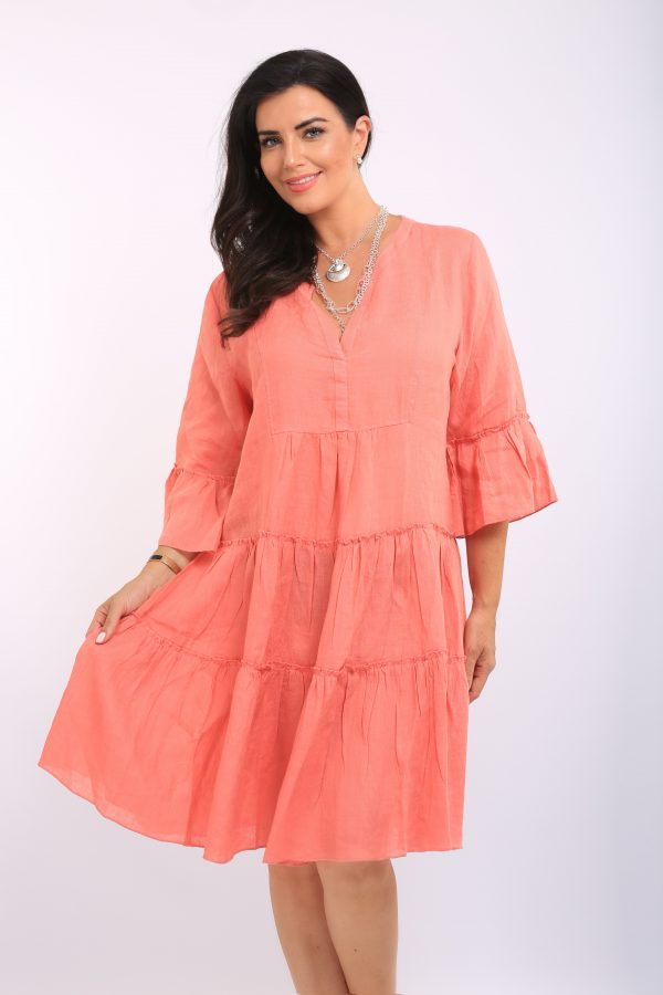 Woman is wearing Orientique plain linen tiered dress in salmon